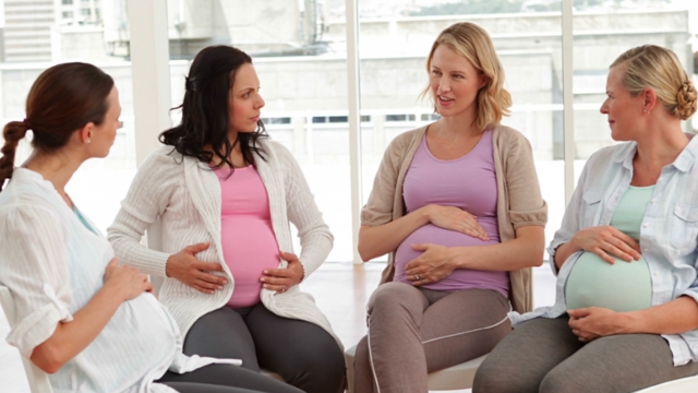 Četri trudnice sede zajedno i razgovaraju